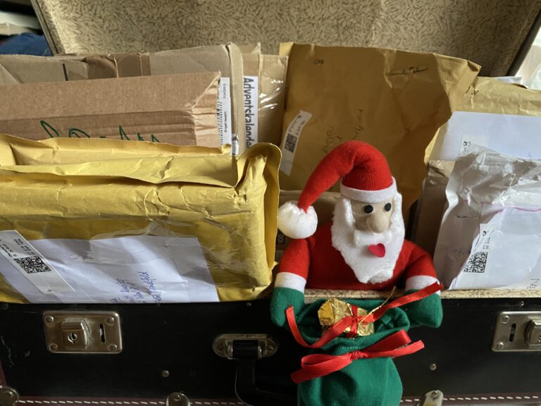 Ein Koffer voller Umschläge und Pakete und ein Stoff Weihnachtsmann
